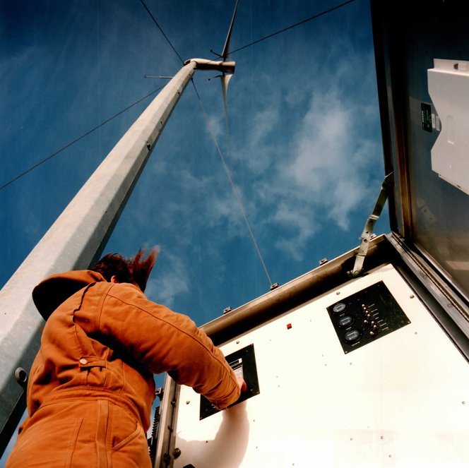 Operator at the base control panel starting the turbine, rotor turning above