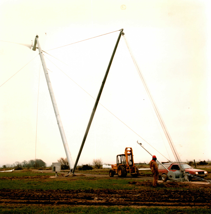 Tilt-up in progress: the gin pole and winch take the tower load — no crane on site, just a forklift and the service vehicle.