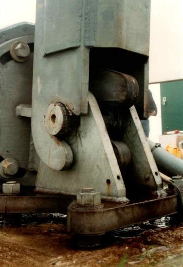 Close-up of the main tower support at the hinged base, showing the pintle, bearing and bolted steel fittings that carry the tower
